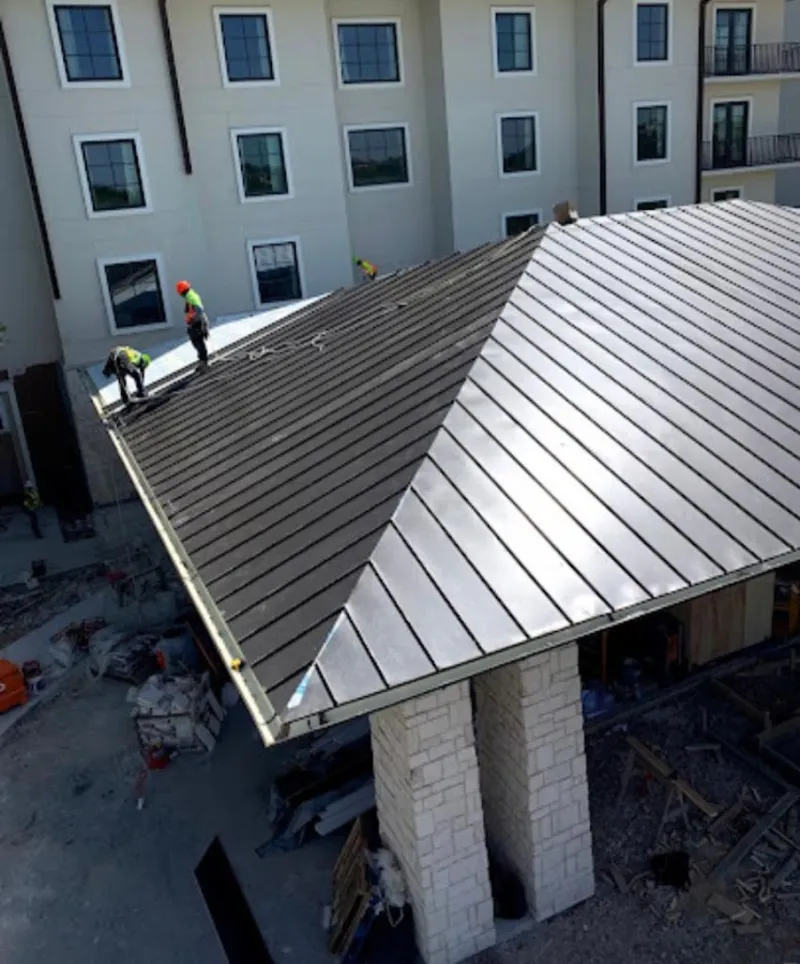 Crew installing standing seam metal roof panels on a commercial project in Wantage